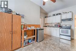 Kitchen featuring white electric stove, light flooring, under cabinet range hood, white cabinetry, and lofted ceiling - 