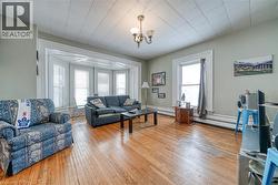 Living room with light wood finished floors, a chandelier, and baseboard heating - 