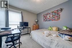 Carpeted bedroom featuring an office area, a paneled ceiling, and a baseboard heating unit - 