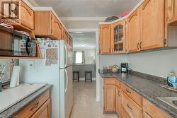 Kitchen with black microwave, dark countertops, ornamental molding, glass insert cabinets, and freestanding refrigerator - 