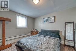 Bedroom featuring a baseboard heating unit and light wood finished floors - 