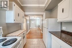 Kitchen with white appliances, white cabinetry, crown molding, and wooden counters - 