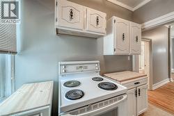 Kitchen with electric stove, butcher block counters, white cabinets, and crown molding - 