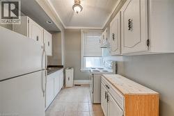 Kitchen featuring white appliances, crown molding, white cabinetry, butcher block countertops, and light tile patterned floors - 