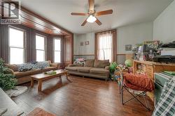 Living area featuring wainscoting, wood-type flooring, wooden walls, and a ceiling fan - 