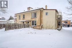 Snow covered back of property featuring brick siding and a chimney - 