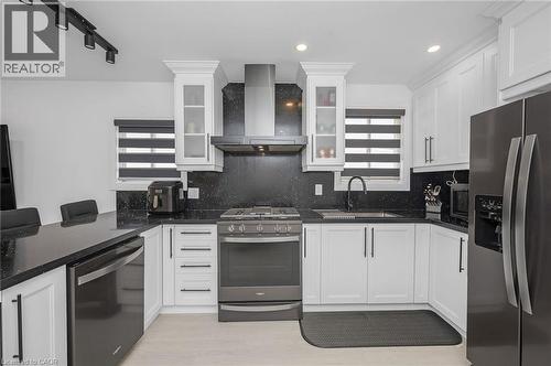 Kitchen with stainless steel appliances, white cabinets, wall chimney range hood, dark stone counters, and recessed lighting - 525 Britannia Avenue, Hamilton, ON - Indoor Photo Showing Kitchen With Stainless Steel Kitchen With Upgraded Kitchen