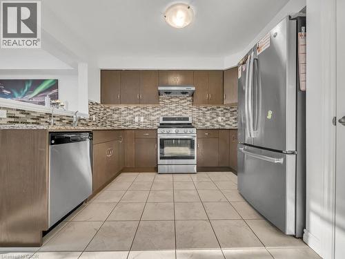Kitchen with appliances with stainless steel finishes, dark stone counters, ventilation hood, decorative backsplash, and dark brown cabinetry - 144 Summit Ridge Drive, Guelph, ON - Indoor Photo Showing Kitchen With Stainless Steel Kitchen With Upgraded Kitchen