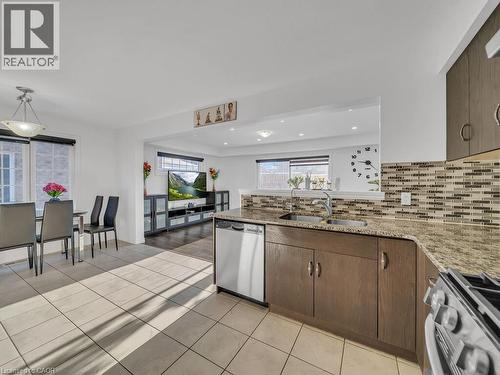 Kitchen with light stone countertops, appliances with stainless steel finishes, decorative backsplash, light tile patterned floors, and recessed lighting - 144 Summit Ridge Drive, Guelph, ON - Indoor Photo Showing Kitchen With Double Sink
