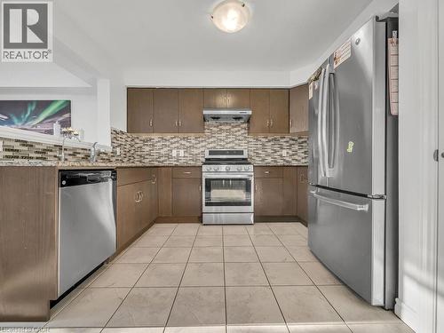 Kitchen featuring stainless steel appliances, dark stone countertops, exhaust hood, and dark brown cabinetry - 144 Summit Ridge Drive, Guelph, ON - Indoor Photo Showing Kitchen With Stainless Steel Kitchen With Upgraded Kitchen