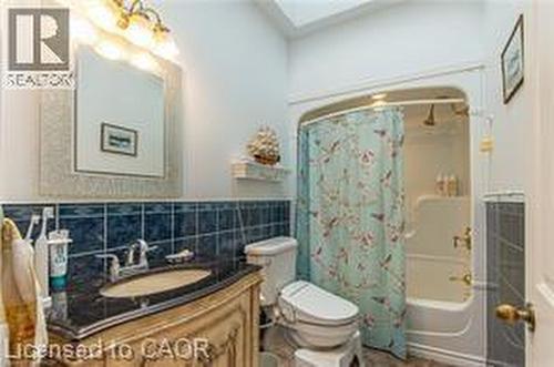 Full bathroom with shower / bathtub combination with curtain, vanity, a skylight, and tile walls - 158 River Run Road, Drayton, ON - Indoor Photo Showing Bathroom