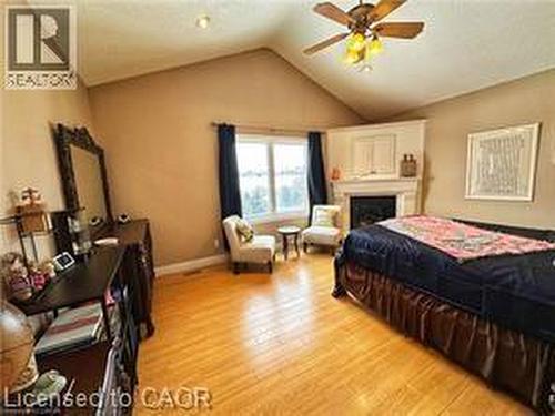 Bedroom with light wood-type flooring, vaulted ceiling, a fireplace, and ceiling fan - 158 River Run Road, Drayton, ON - Indoor Photo Showing Bedroom