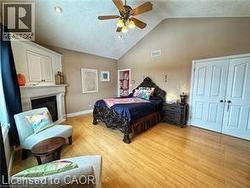 Bedroom with light wood-type flooring, a ceiling fan, and high vaulted ceiling - 