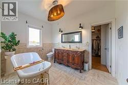 Bathroom with vanity, a soaking tub, a walk in closet, tile walls, and wainscoting - 