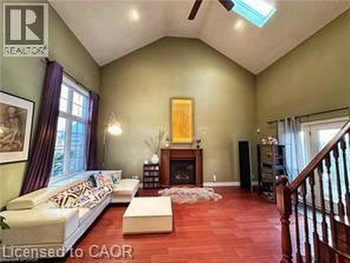 Living area featuring a skylight, a fireplace with raised hearth, a ceiling fan, wood finished floors, and stairway - 158 River Run Road, Drayton, ON - Indoor With Fireplace