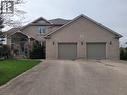 Light grey brick exterior featuring a covered front entry with columns, a two-car garage with individual doors, and a paved driveway - 158 River Run Road, Drayton, ON  - Outdoor 