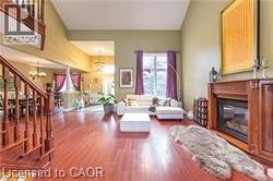 Living room with a glass covered fireplace, wood finished floors, and a chandelier - 