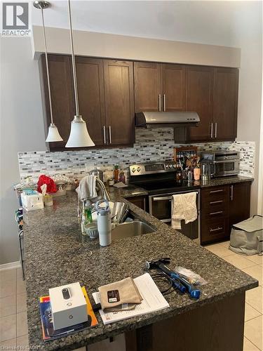 Kitchen featuring light tile patterned floors, range, dark brown cabinets, dark stone countertops, and ventilation hood - 229 Pine Glen Crescent, Kitchener, ON - Indoor Photo Showing Kitchen With Upgraded Kitchen