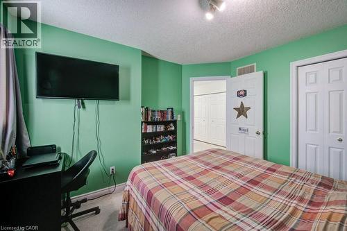 Carpeted bedroom featuring a textured ceiling, a desk, and a closet - 711 Southwood Way, Woodstock, ON - Indoor Photo Showing Bedroom