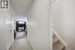 Corridor with stairs, a textured ceiling, and light colored carpet - 