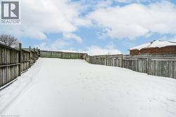 Yard layered in snow with a fenced backyard - 
