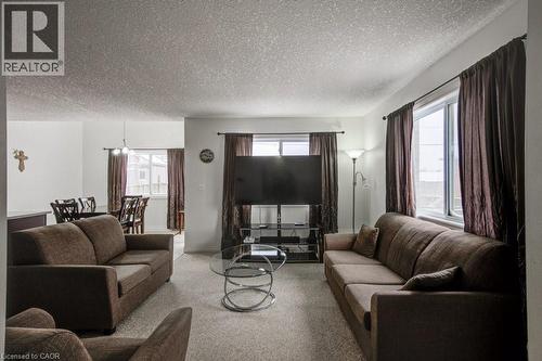 Carpeted living area with a textured ceiling and healthy amount of natural light - 711 Southwood Way, Woodstock, ON - Indoor Photo Showing Living Room