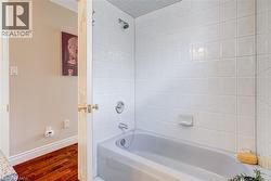 Bathroom featuring shower / tub combination and dark wood-style flooring - 