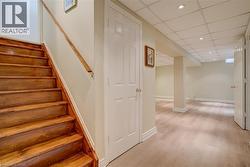 Staircase featuring a paneled ceiling, recessed lighting, and wood finished floors - 
