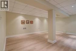 Finished below grade area featuring a paneled ceiling and light wood-style floors - 