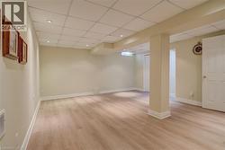 Finished basement with light wood-type flooring, a drop ceiling, and recessed lighting - 