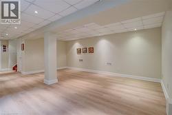 Finished below grade area featuring recessed lighting, a paneled ceiling, and light wood finished floors - 