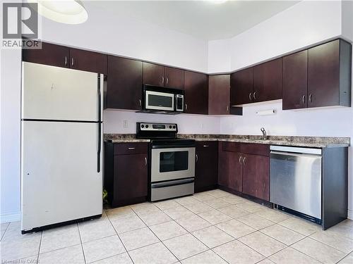 Kitchen with stainless steel appliances, dark wood finish cabinetry, and dark countertops - 5053 Bidwell Common, Burlington, ON - Indoor Photo Showing Kitchen