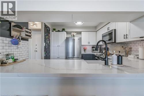 Kitchen featuring white cabinets, backsplash, appliances with stainless steel finishes, and light stone counters - 3845 Lakeshore Boulevard W Unit# 804, Etobicoke, ON - Indoor Photo Showing Kitchen With Stainless Steel Kitchen With Upgraded Kitchen