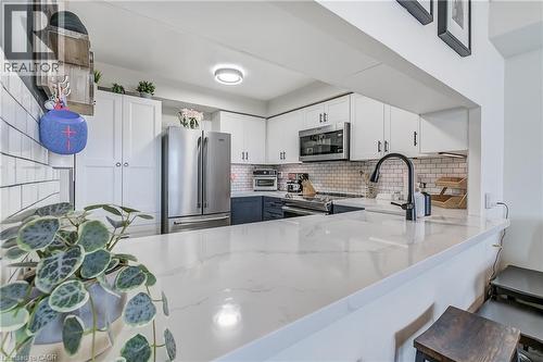 Kitchen with white cabinets, appliances with stainless steel finishes, decorative backsplash, light stone counters, and a kitchen bar - 3845 Lakeshore Boulevard W Unit# 804, Etobicoke, ON - Indoor Photo Showing Kitchen With Stainless Steel Kitchen With Upgraded Kitchen