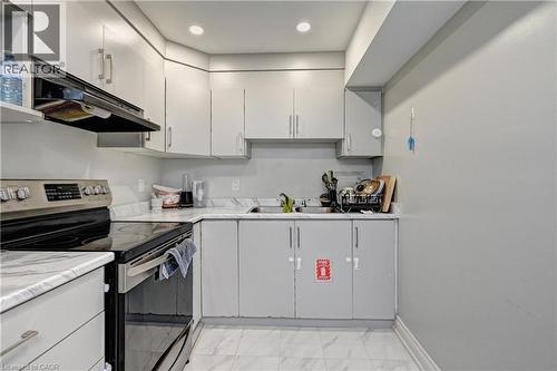 Kitchen featuring stainless steel range with electric cooktop, under cabinet range hood, light countertops, light marble finish flooring, and recessed lighting - 32 Weir Street, Cambridge, ON - Indoor Photo Showing Kitchen With Double Sink