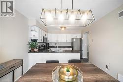 Kitchen featuring stainless steel appliances, white cabinetry, decorative light fixtures, a peninsula, and open shelves - 