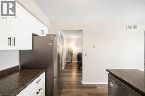 Kitchen featuring stainless steel appliances, dark wood finished floors, white cabinets, and decorative backsplash - 25 Meadowvale Drive Unit# 3, Fonthill, ON - Indoor Photo Showing Kitchen