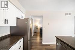 Kitchen featuring stainless steel appliances, dark wood finished floors, white cabinets, and decorative backsplash - 