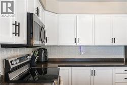Kitchen with appliances with stainless steel finishes, white cabinetry, and backsplash - 
