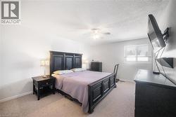 Bedroom featuring light carpet, ceiling fan, and a textured ceiling - 