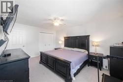 Bedroom with light colored carpet, a closet, ceiling fan, and a textured ceiling - 