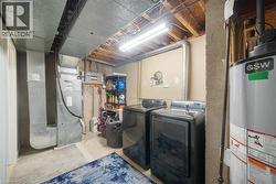 Laundry area with water heater, heating unit, unfinished concrete floors, and separate washer and dryer - 