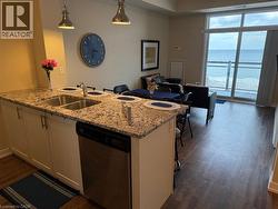 Kitchen with light stone countertops, a breakfast bar, dishwasher, and white cabinets - 