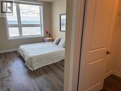 Bedroom with dark wood-style flooring and a water view - 