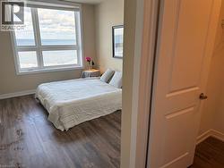 Bedroom with a water view and dark wood-type flooring - 