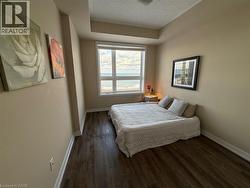Bedroom with dark wood-style floors and a textured ceiling - 