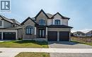 French provincial home with brick siding, decorative driveway, a front lawn, an attached garage, and french doors - 7266 Silver Creek Circle, London, ON  - Outdoor With Facade 