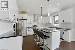 Kitchen featuring a breakfast bar, white cabinetry, pendant lighting, dark wood-style flooring, and recessed lighting - 