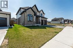 French country home featuring brick siding, a front yard, a garage, and concrete driveway - 