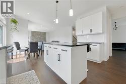 Kitchen featuring white cabinetry, decorative light fixtures, dark wood-style flooring, and recessed lighting - 